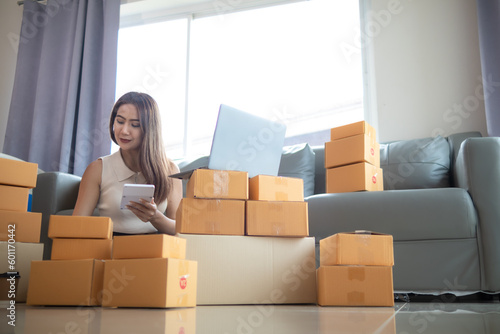 woman checking package of goods from customer online order is alone in her home office as she is an SME entrepreneur and uses her phone and tablet to market online. concept online sales business