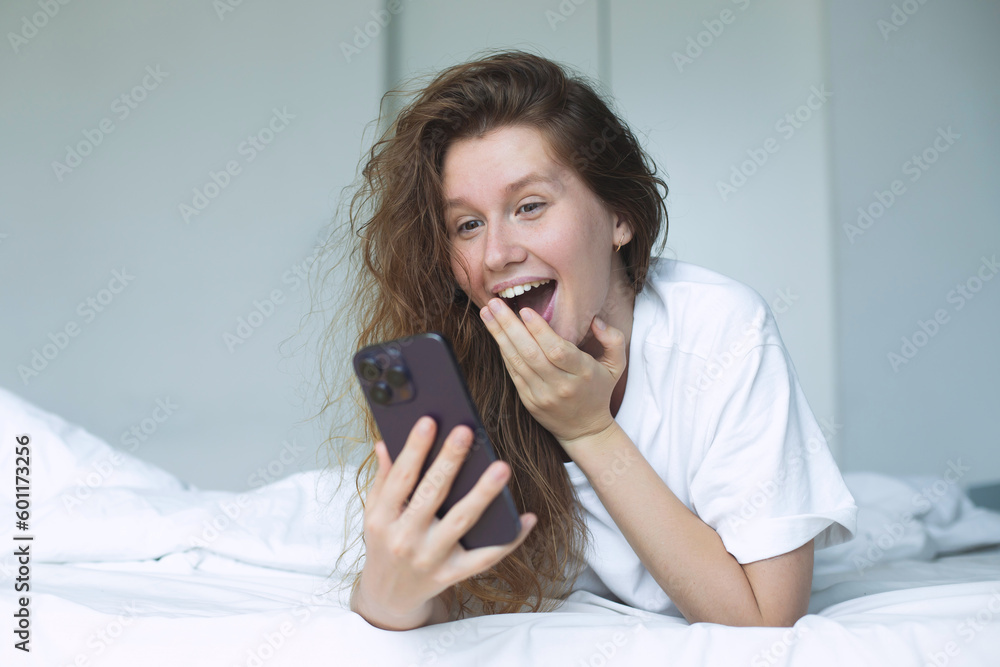 young happy woman use phone and lying in bed in bedroom in the morning, concept morning, phone addiction, social, habits young happy woman use phone and lying in bed in bedroom in the morning, concept morning, phone addiction, social, habits