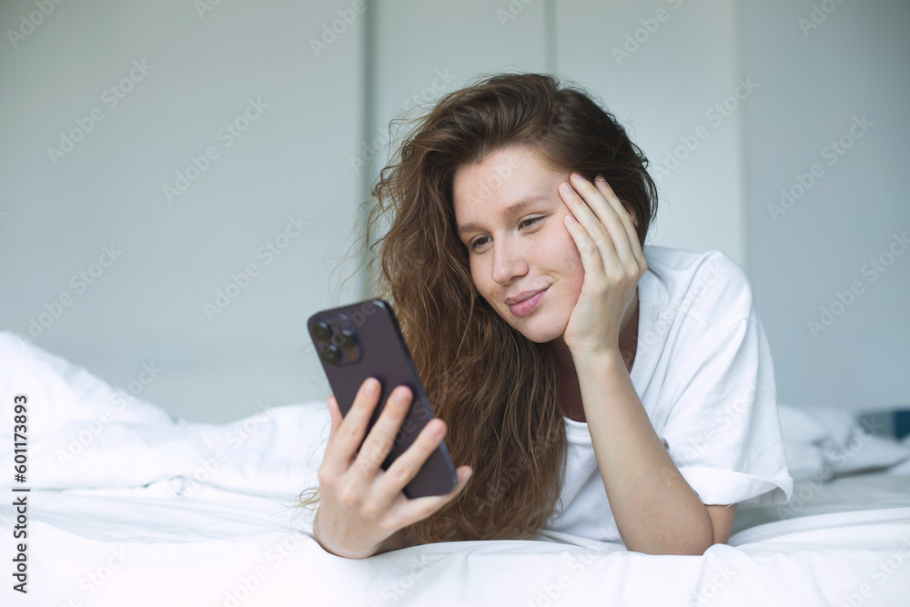 young happy woman use phone and lying in bed in bedroom in the morning, concept morning, phone addiction, social, habits young happy woman use phone and lying in bed in bedroom in the morning, concept morning, phone addiction, social, habits