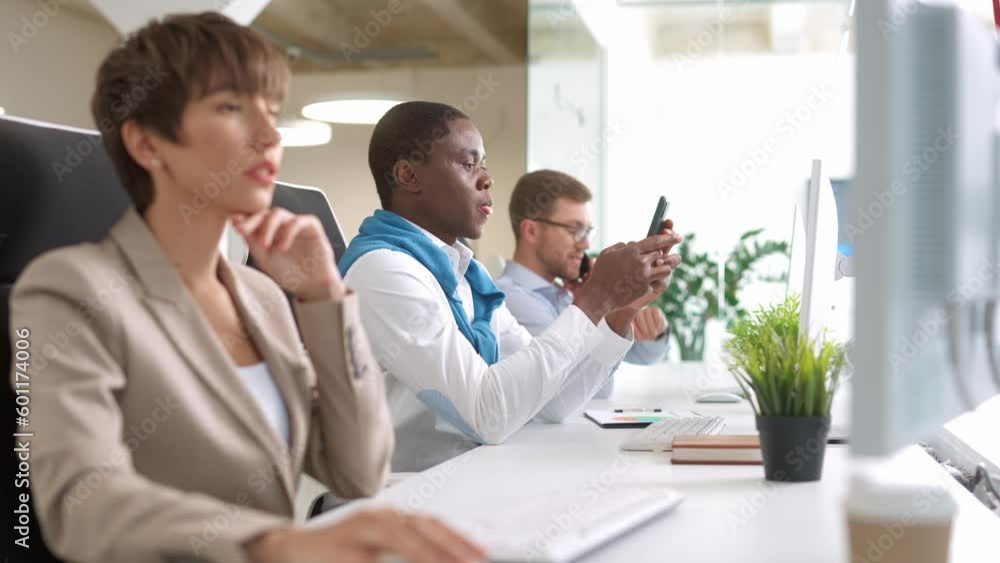 Group of young multiethnic people working in business center. Hardworking men using telephone while busy woman working on computer. People using technology. Concept of office teamwork. Group of young multiethnic people working in business center. Hardworking men using telephone while busy woman working on computer. People using technology. Concept of office teamwork.