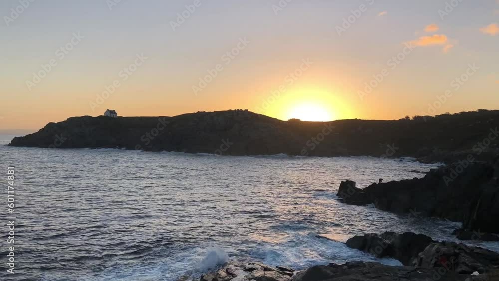 Sunrise with a fisherman on the rocks and the Phare du Millier over the cliff, Brittany, France