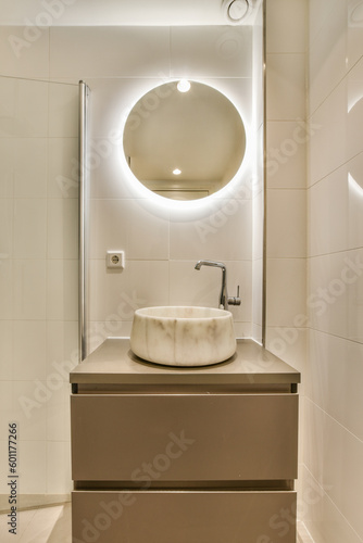 a bathroom with a sink and mirror on the wall next to it is an illuminated round light above the sink
