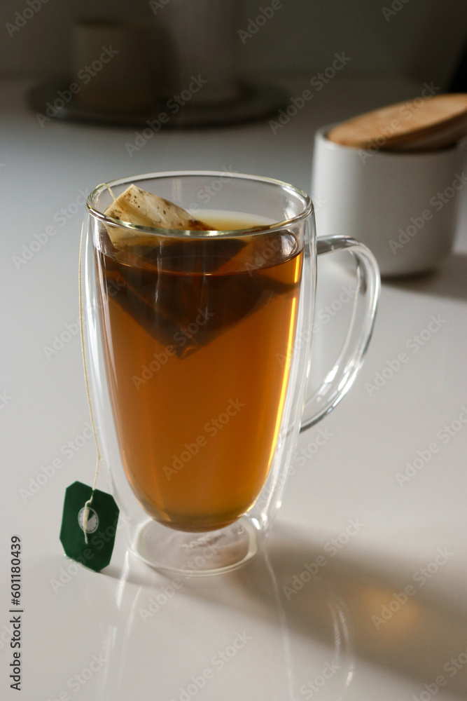 close up of a glas cup of black tea, flowers in background close up of a glas cup of black tea, flowers in background