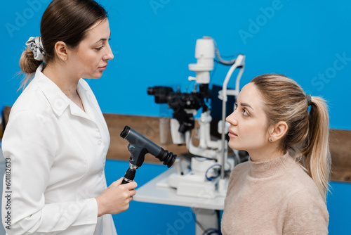 Ophthalmoscopy. Consultation with optometrist in medical clinic. Ophthalmologist examines the eyes of woman with ophthalmoscope. Ophthalmology.