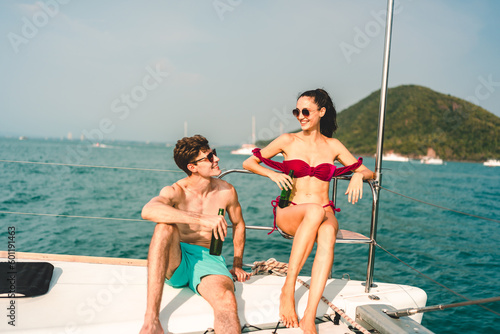 Caucasian couple who man and woman relax fun with luxury party drinking champagne by talking together while catamaran yacht boat sailing. Happy and enjoy outdoor lifestyle on summer vacation travel