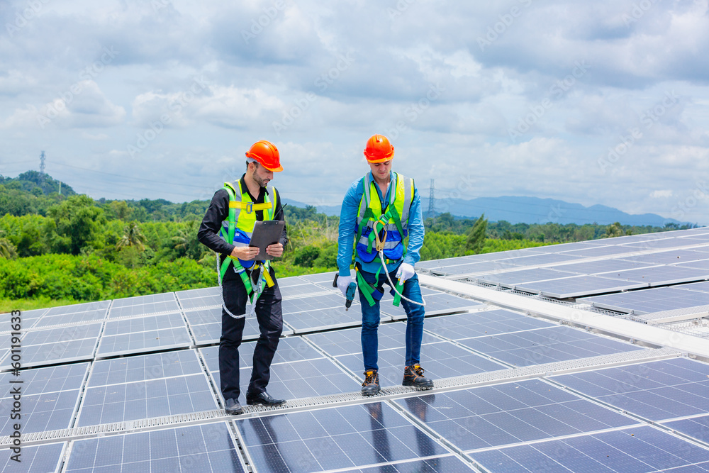 Technician engineer planning to setting solar panel on the roof of the building to work at full efficiency, Using solar cells for energy saving to save and protect environment. Renewable energy