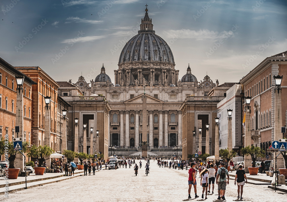 Perspektywa z poziomu ulicy Via della Conciliazione prowadząca bezpośrednio do majestatycznej Bazyliki Świętego Piotra w Rzymie. Starożytne budynki i historyczna atmosfera dodają uroku tej malowniczej - obrazy, fototapety, plakaty 