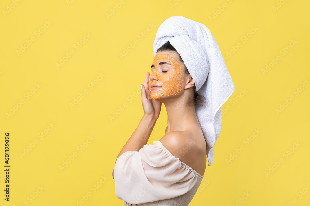 A pretty young girl with a scrub mask on her face poses for the camera and smiles against a yellow background. A pretty young girl with a scrub mask on her face poses for the camera and smiles against a yellow background.
