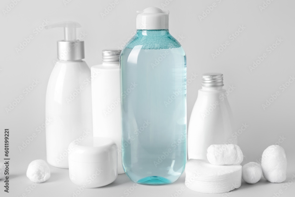 Micellar water with cosmetic products, cotton balls and pads on light background Micellar water with cosmetic products, cotton balls and pads on light background