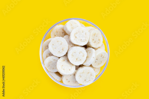 Banana slices in bowl on yellow background.