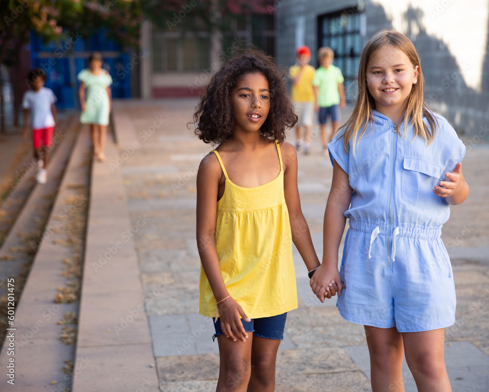 Two tween girls spending time together in summer, talking friendly, enjoying walking around city..