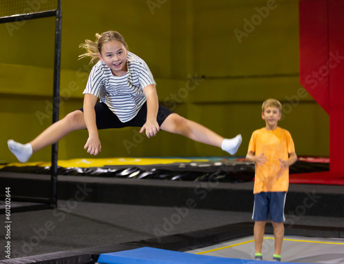 Playful girl jumping on trampoline at playground indoor