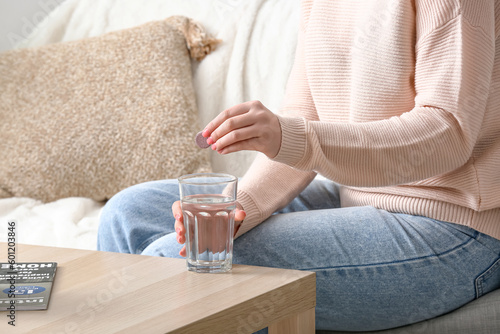 Woman putting effervescent tablet into glass of water
