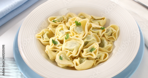 tortelloni on a plate. classic italian pasta with spinach and ricotta on a light background. dish of mediterranean cuisine. food on the table on a sunny day.