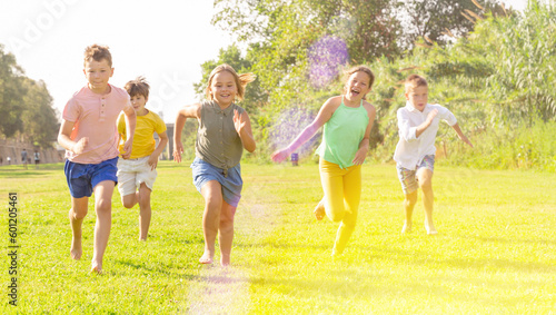 Portrait of five smiling preteen kids running in race and laughing in park © JackF