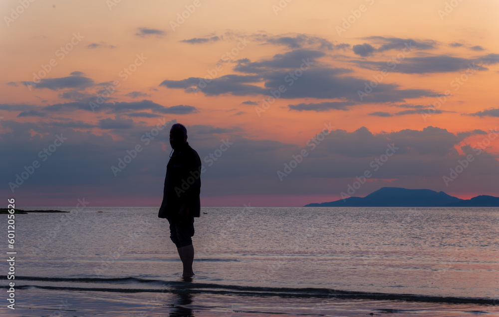 Silhouette of a man on the beach during sunset, photograph in orange tones.