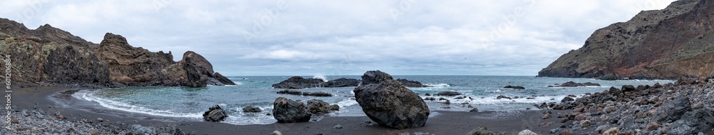 Huge amazing panorama shot of black sand beach and rocks surrounded by mountains and little bay in tenerife, canarias, spain