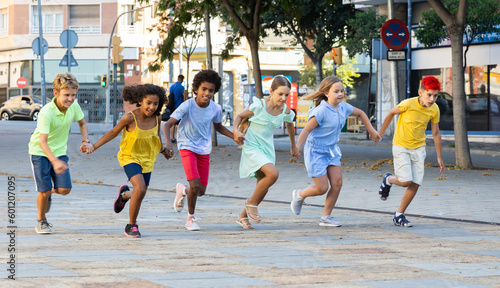 Happy children running together hand in hand through streets. Cheerful kids on summer vacation.