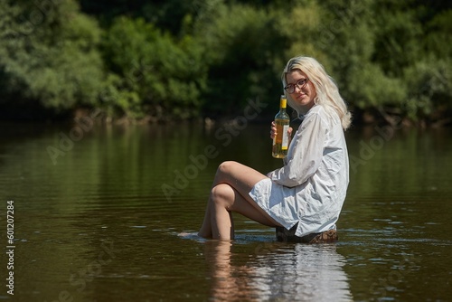 Woman on a river with bottle of wine