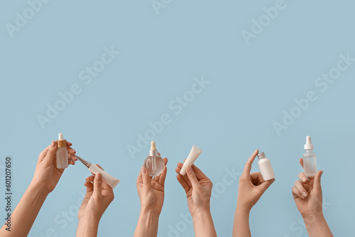 Hands holding different cosmetic products on light blue background