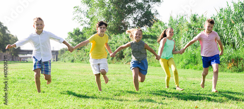 Barefoot kids running on green grass on field in summertime.