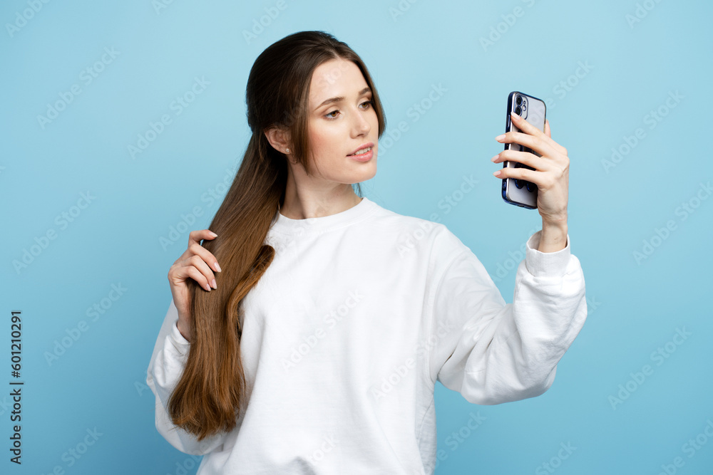 Lovely brunette woman in white shirt with charming smile using cellphone making selfie Lovely brunette woman in white shirt with charming smile using cellphone making selfie