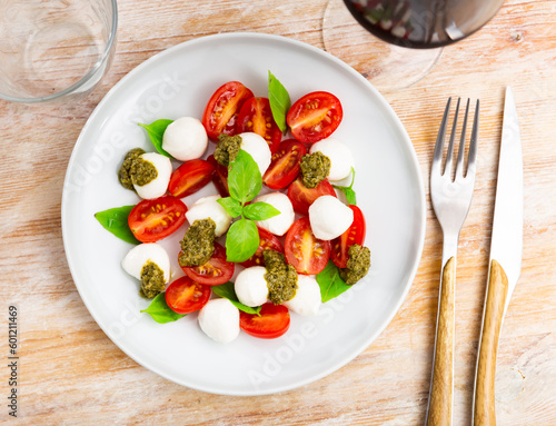 Caprese salad with basil and pesto sauce served on plate. Traditional Italian salad.