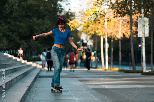 bella mujer adolescente estilo 80s 90s andando en skate en la ciudad, con maquillaje, anteojos y jeans. en un día soleado al atardecer.