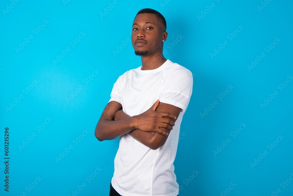 Portrait of Handsome man wearing white T-shirt over blue background standing with folded arms and smiling Portrait of Handsome man wearing white T-shirt over blue background standing with folded arms and smiling