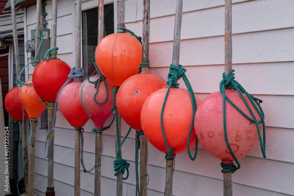 A row of orange colored rubber fishing net markers tied to long wooden