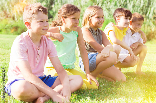 Positive preteen childs, boys and girls, standing at a park in summer outside