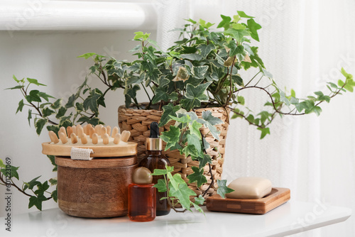 Obraz na plátně Massage brush, different cosmetic products and houseplant on table in bathroom