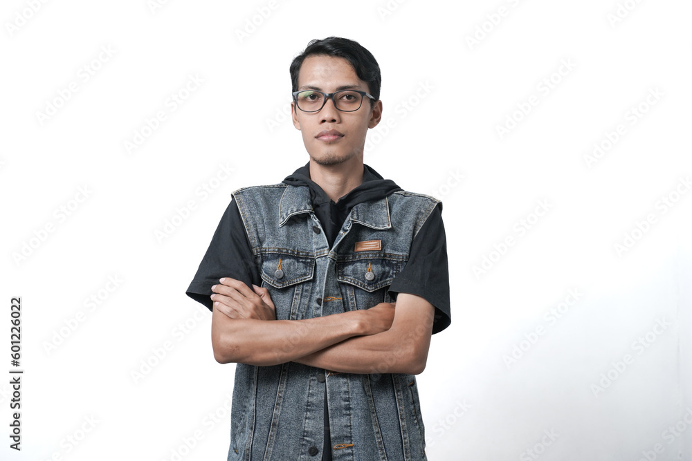 Asian man wearing sleeveless blue jean jacket crossed arms positive expression. Isolated white background Asian man wearing sleeveless blue jean jacket crossed arms positive expression. Isolated white background
