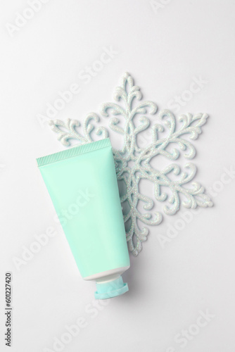 Winter skin care. Hand cream and decorative snowflake on white background, top view