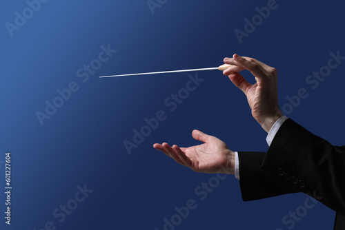 Professional conductor with baton on blue background, closeup photo