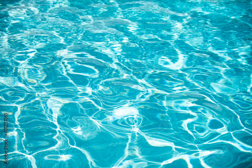 Water background. Blue water  ripples and highlights. Texture of water surface and tiled bottom.
