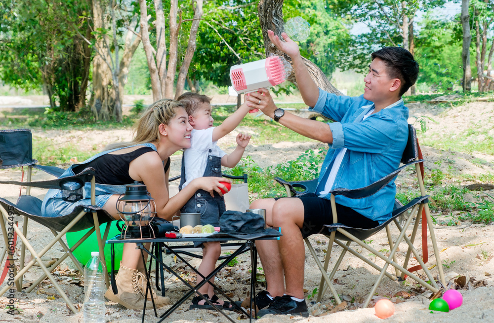 Asian family having fun in park. They are blowing bubbles happily. Bonding and togetherness concept Asian family having fun in park. They are blowing bubbles happily. Bonding and togetherness concept