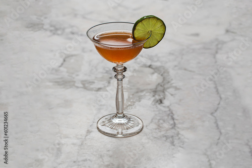 Classic fancy coupe drink on fancy marble top in cocktail lounge with lime wheel garnish