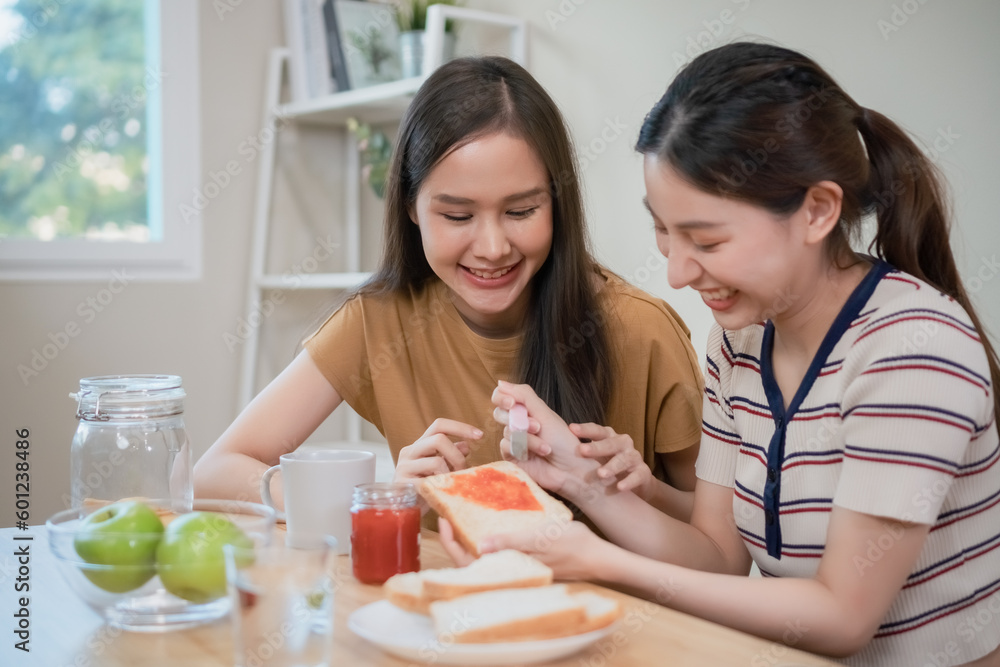 happy asian female couple have breakfast at table kitchen. two beautiful woman eating food in morning. happy asian female couple have breakfast at table kitchen. two beautiful woman eating food in morning.
