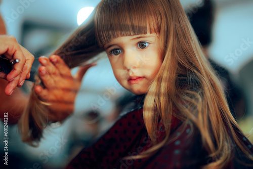 Adorable Toddler Girl Getting her Hair Cute in a Professional Salon. Little preschool child having a haircut in a beauty studio 