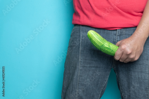 man hand holding cucumber. concept of man erection or hard penis isolated blue background photo