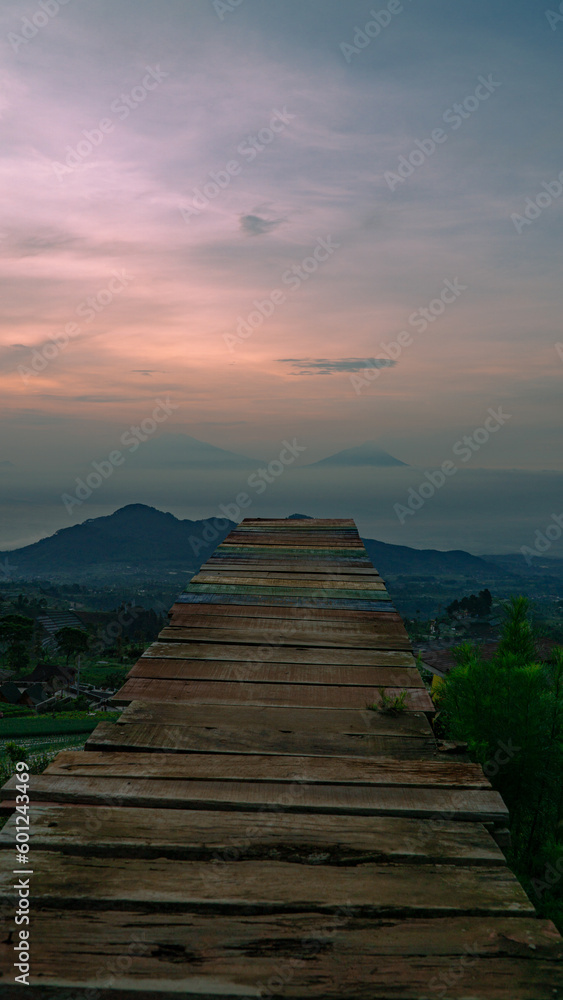 Beautiful reddish orange sunrise sky with mountain range and plantation on the foreground -  Mangli Sky View Tourist attraction on slope  Sumbing Mountain, Indonesia