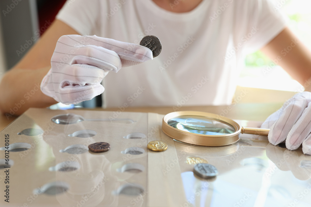 Woman numismatist examining coin with magnifier Woman numismatist examining coin with magnifier