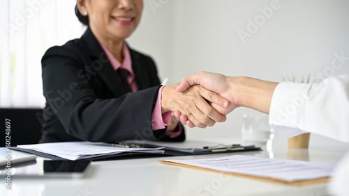 A businesswoman shaking hands with a candidate after a job interview.