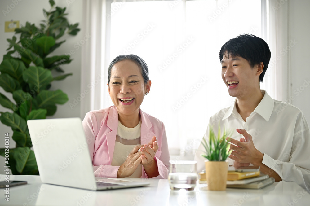 Cheerful senior Asian female manager and a young male office worker applauding Cheerful senior Asian female manager and a young male office worker applauding