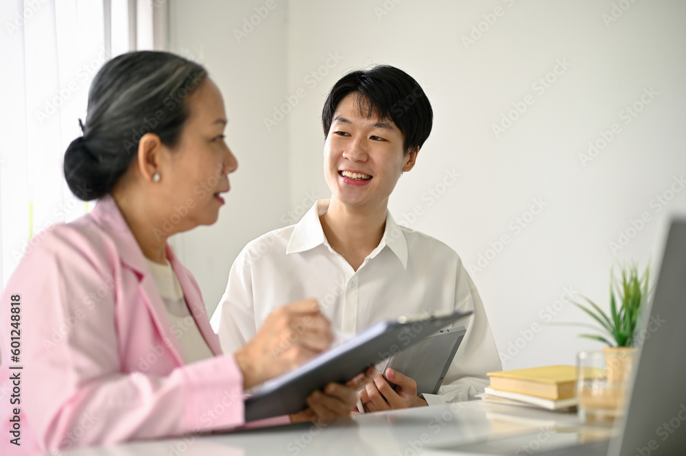 Smart Asian male office worker talking and sharing his idea to a senior female manager Smart Asian male office worker talking and sharing his idea to a senior female manager