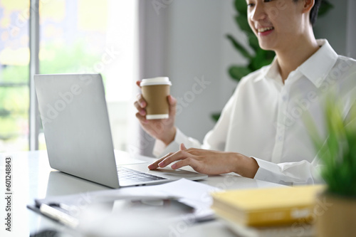 Close-up image of a professional Asian businessman sipping coffee and using his laptop