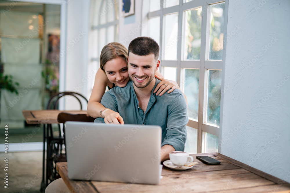 Loving couple hugging and looking at laptop. The concept of couples sharing one idea together. Loving couple hugging and looking at laptop. The concept of couples sharing one idea together.
