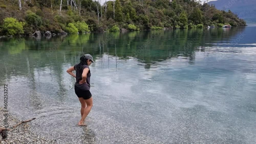 Latin woman Wading into cold water on the bobs cove walk in lake wakatipu Latin woman Wading into cold water on the bobs cove walk in lake wakatipu