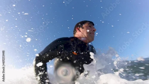 POV: A young and experienced man surfer rides a wave in a wet suit on a sunny day in Carcavelos beach. Europe. Great snap or layback or carving. photo